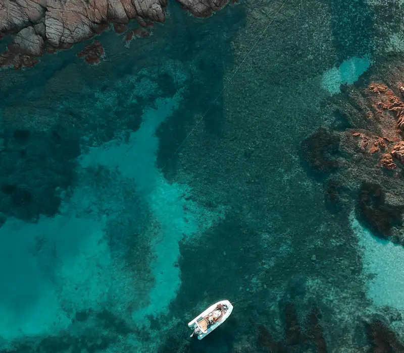 Turquoise cove from above, with a boat at anchor